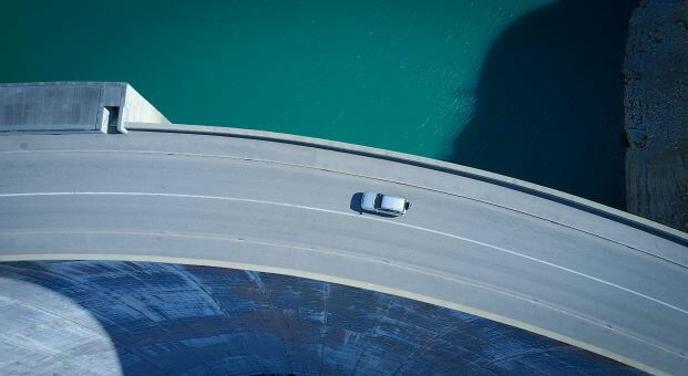 A highway with a single car driving over an ocean view